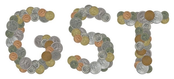 GST word with stack of coins on white background
