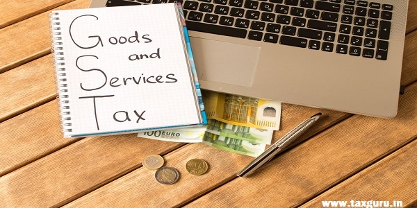 Goods and Services Tax GST- Laptop, pen, coins, banknotes on wood background