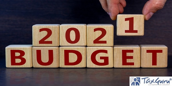 Male hand puts a wooden cube on other cubes with the word Budget 2021