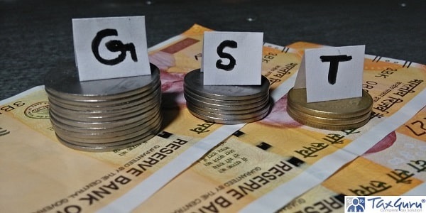 GST written on separate paper folds that are put over the pile of 2,1 and rupee coins