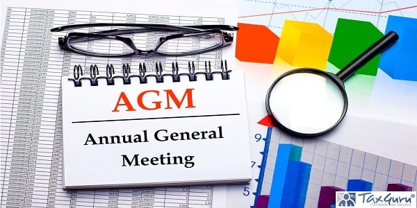 On the desktop are glasses, a magnifying glass, color charts and a white notebook with the text AGM Annual General Meeting