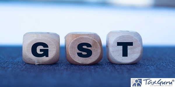 GST in 3d wooden alphabet letters on a blue background with copy space, business concept