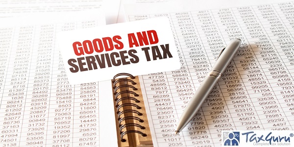Text GST GOODS AND SERVICES TAX on paper card,pen, financial documentation on table