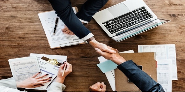 Business Agreement Finalized with a Handshake Over Financial Documents